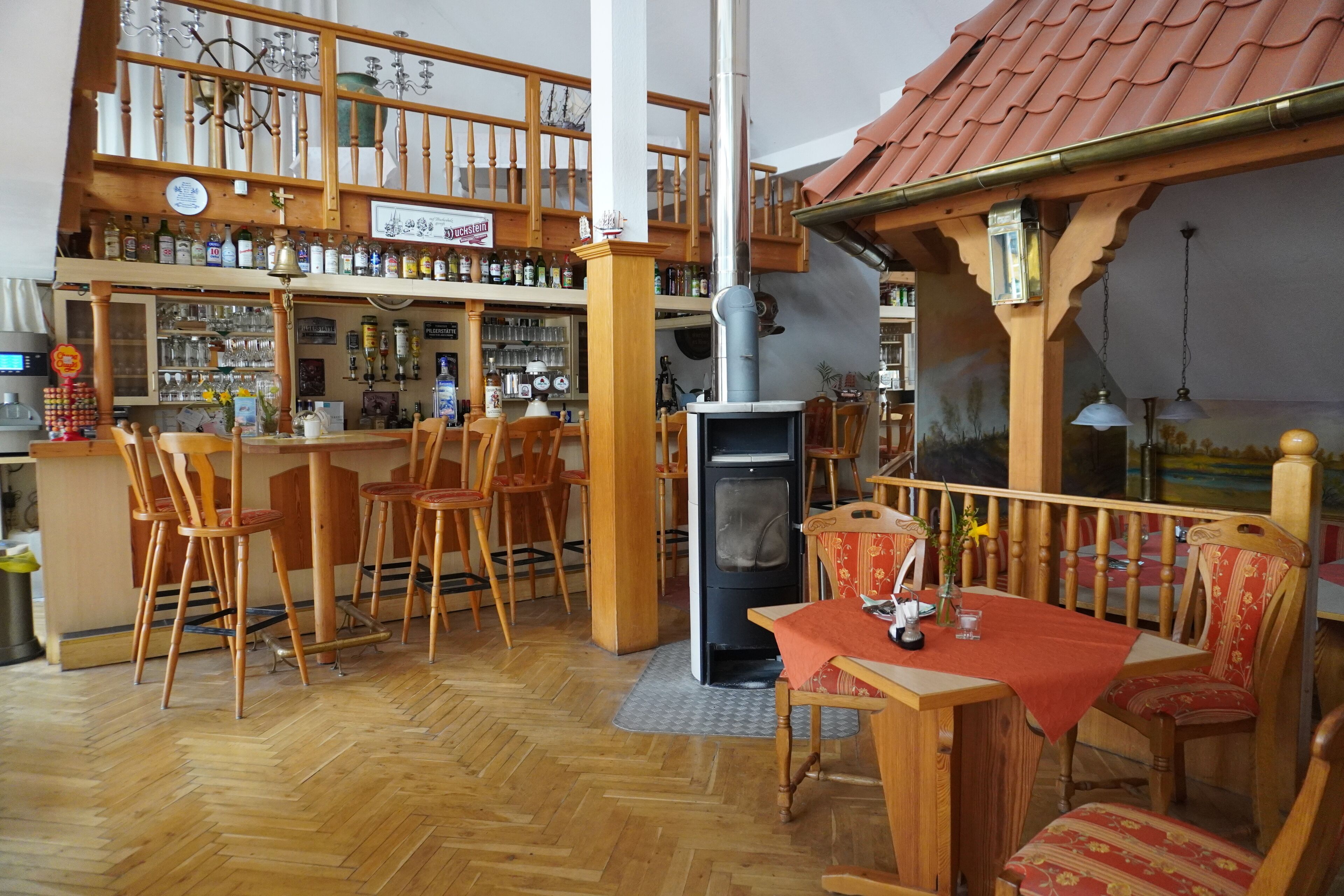 A bar area with wooden furniture, a fireplace, and a variety of bottles on shelves.