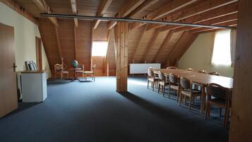 Une vaste pièce mansardée avec un haut plafond en bois, une longue table à manger et plusieurs chaises.