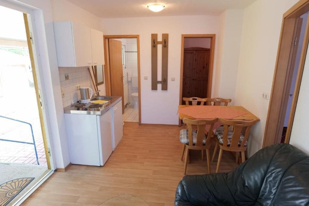 Una cucina compatta con zona pranzo, un divano in pelle nera e un tavolo in legno.