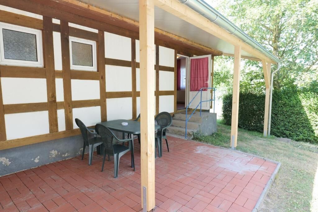 Un patio cubierto con suelo de ladrillo, vigas de madera y una mesa con sillas.