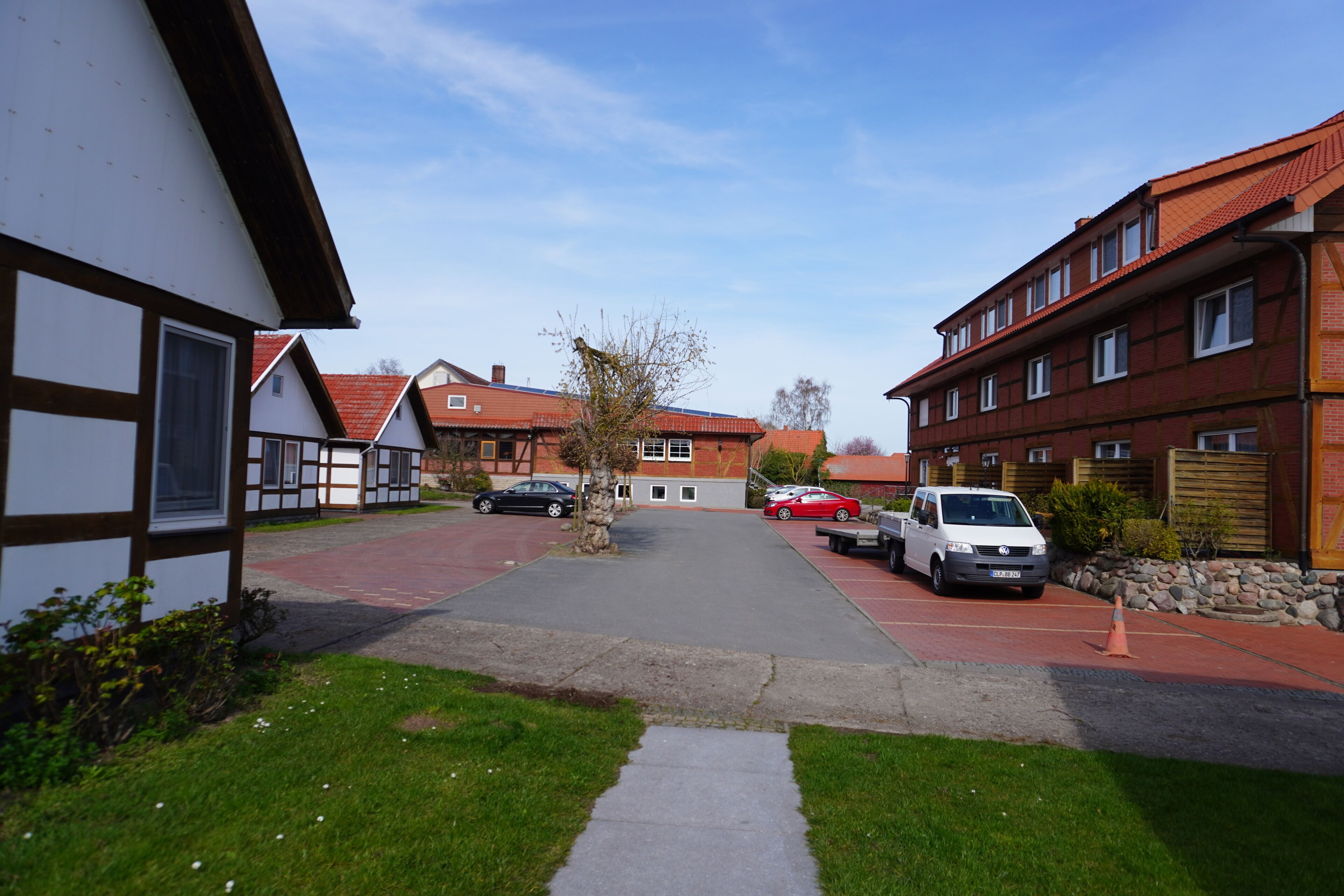 Eine Wohnstraße mit Häusern, parkenden Autos und blauem Himmel.