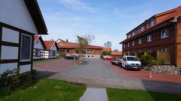 Eine Wohnstraße mit Häusern, parkenden Autos und blauem Himmel.