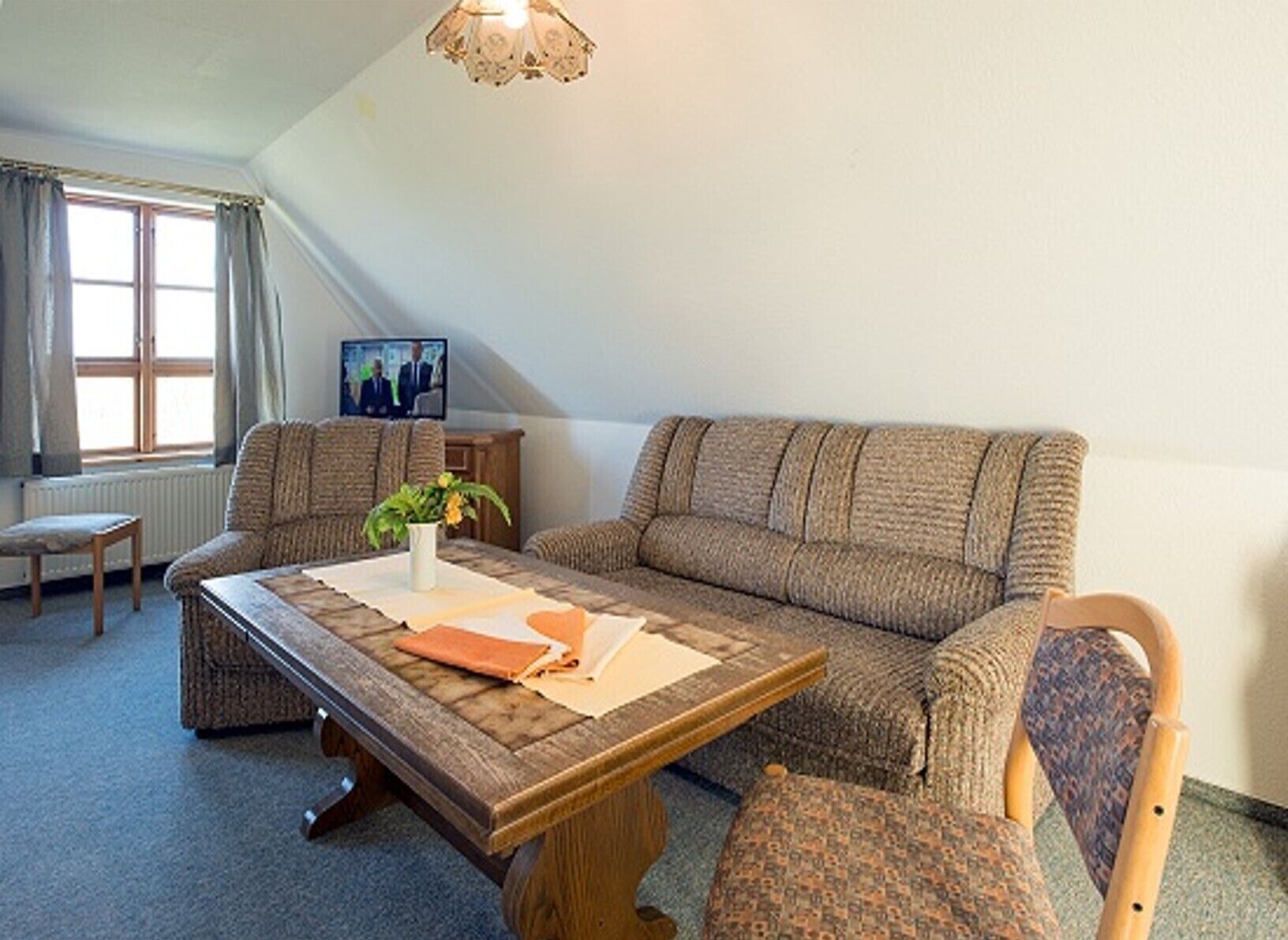 A cozy living room with a sofa, armchairs, a coffee table, and a television.