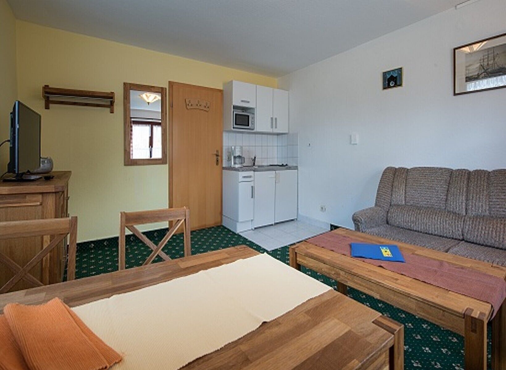 A compact living space with a kitchenette, a sofa, a dining table, and a TV.