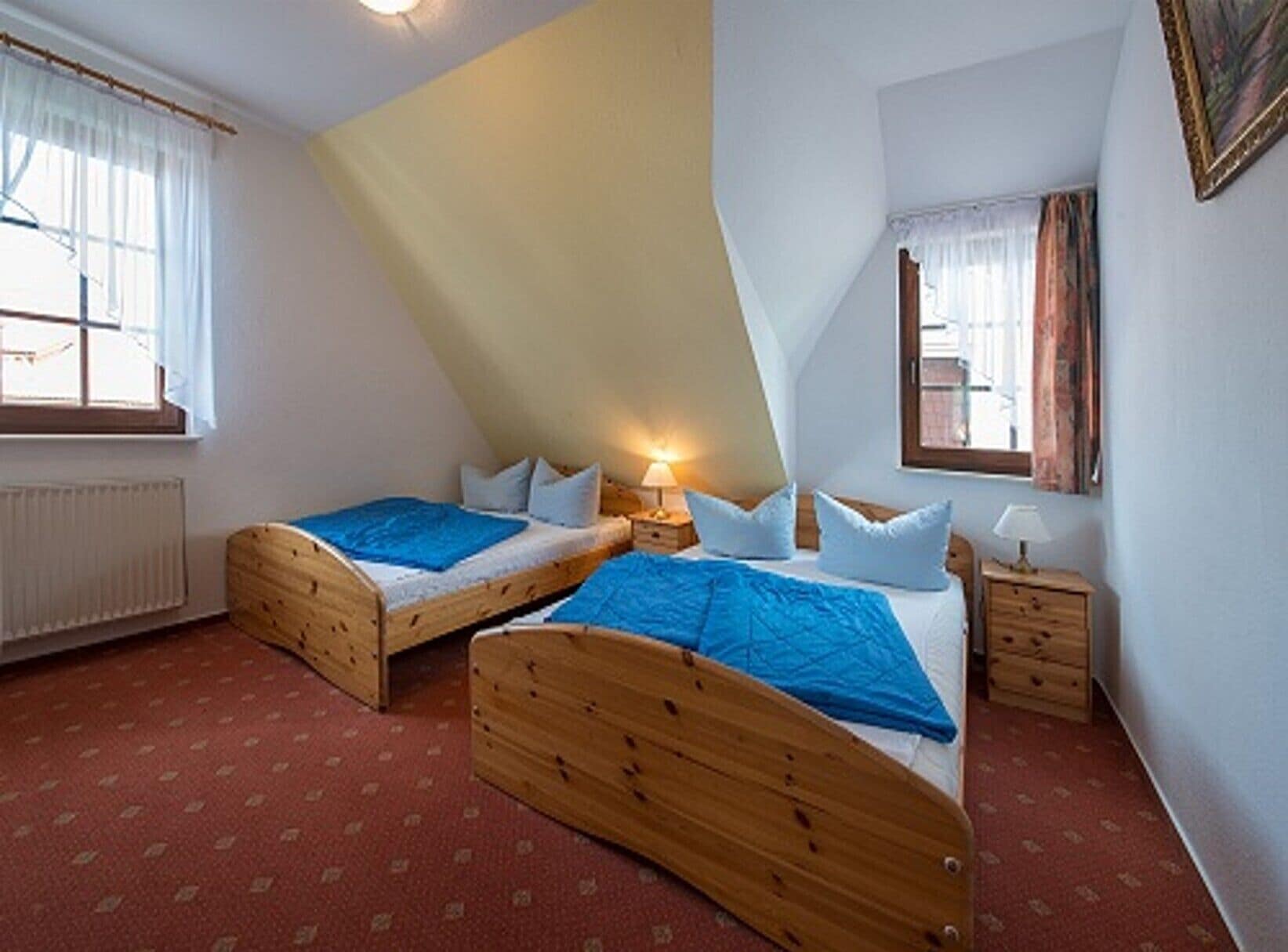 Ein Schlafzimmer mit zwei Holzbetten, einem Heizkörper und einem Fenster mit Vorhängen.