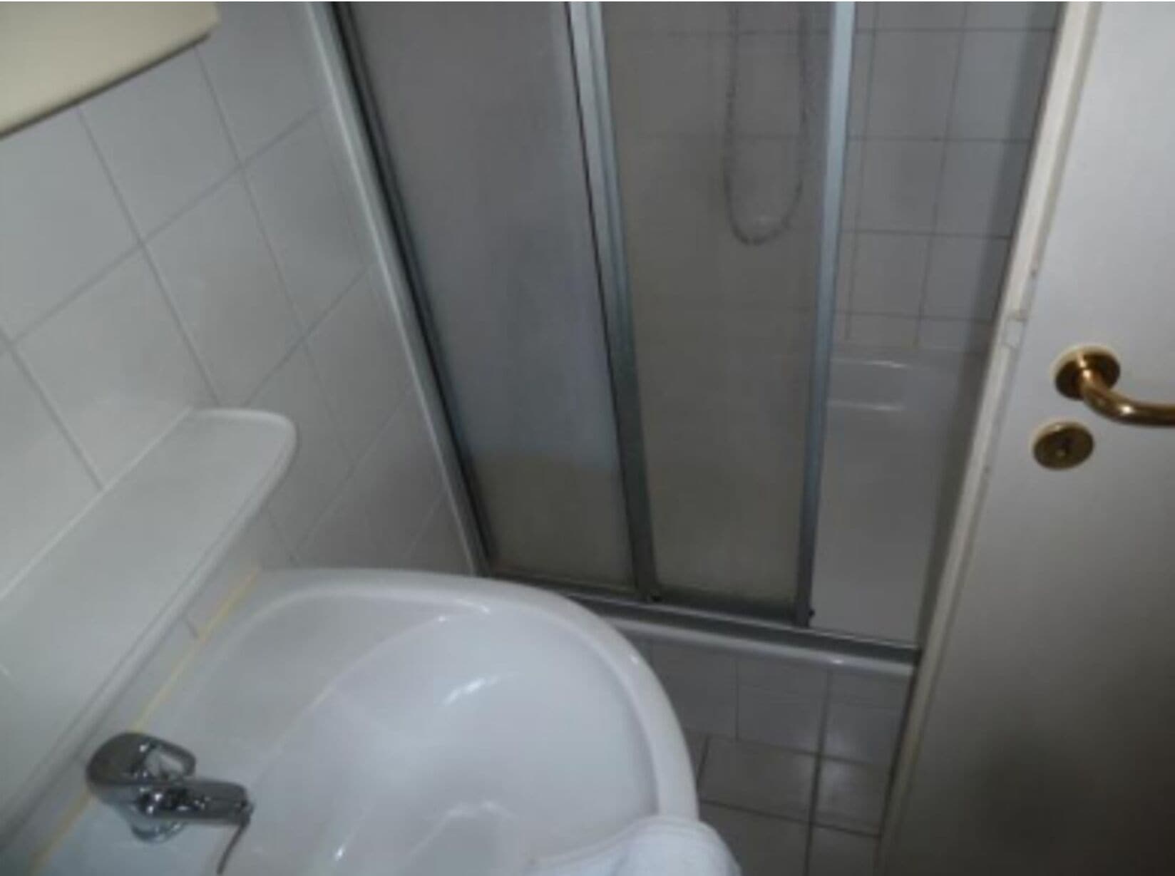 Ein Badezimmer mit Duschkabine, Waschbecken und Toilette.
