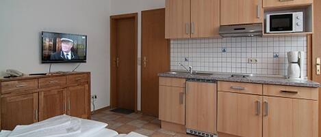 A compact kitchen with wooden cabinets, a microwave, and a tiled backsplash.