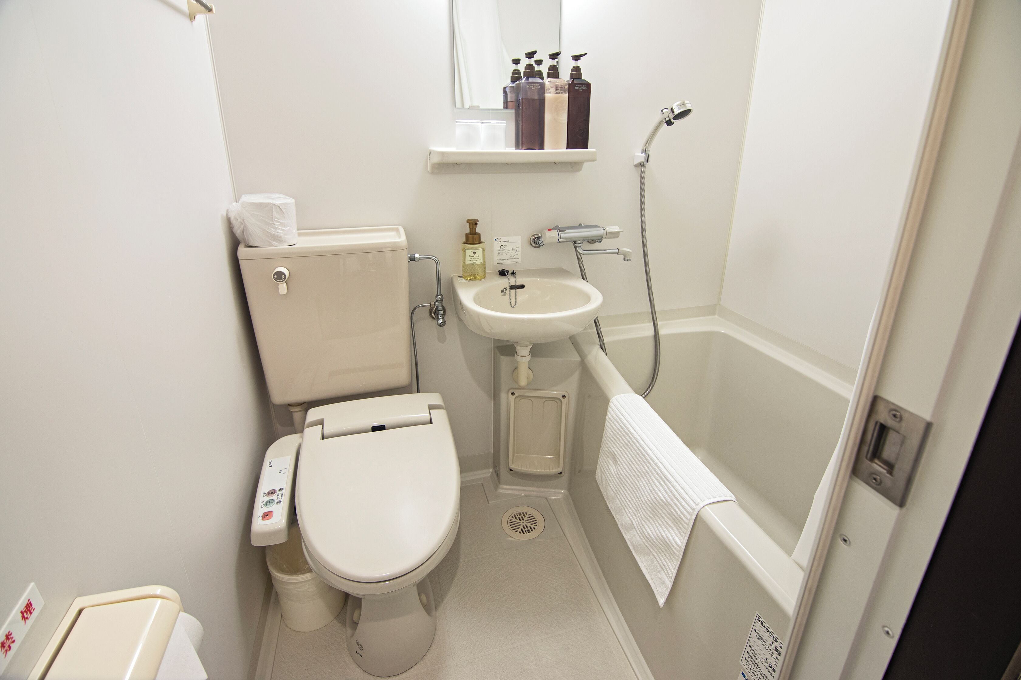 Un baño pequeño y limpio con inodoro, lavamanos y ducha.