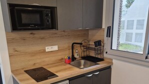 A compact kitchen with a built-in microwave, a small sink, and a dishwasher. - À Louer Dans le Centre de Boulogne-billancourt à 10 mn en bus de Paris16éme (Boulogne-Billancourt)