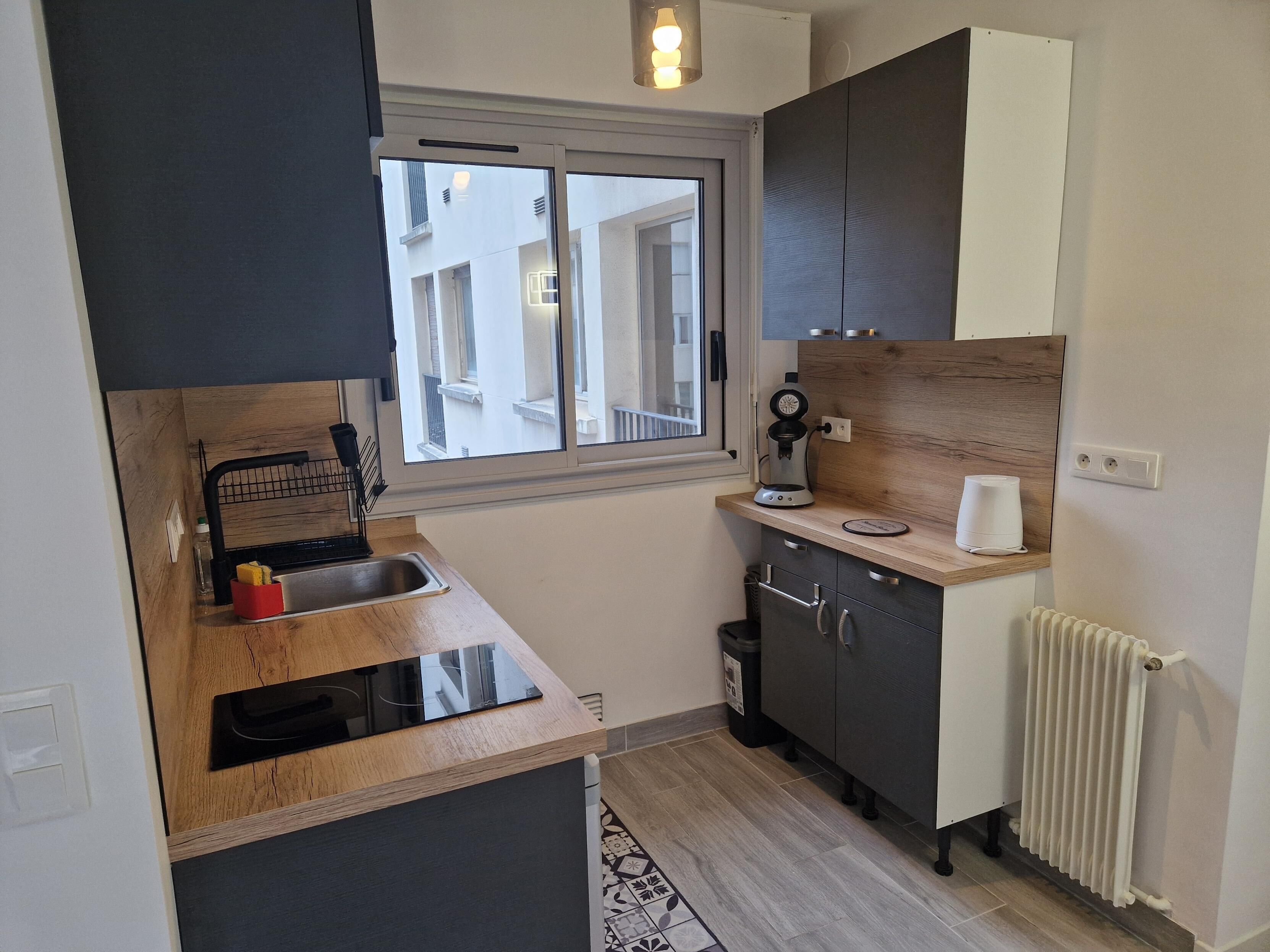 Una cocina compacta con ventana, cafetera y horno integrado.