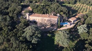 Un vaste domaine comprenant un bâtiment principal entouré d’une forêt dense, une piscine et des champs en terrasses.
