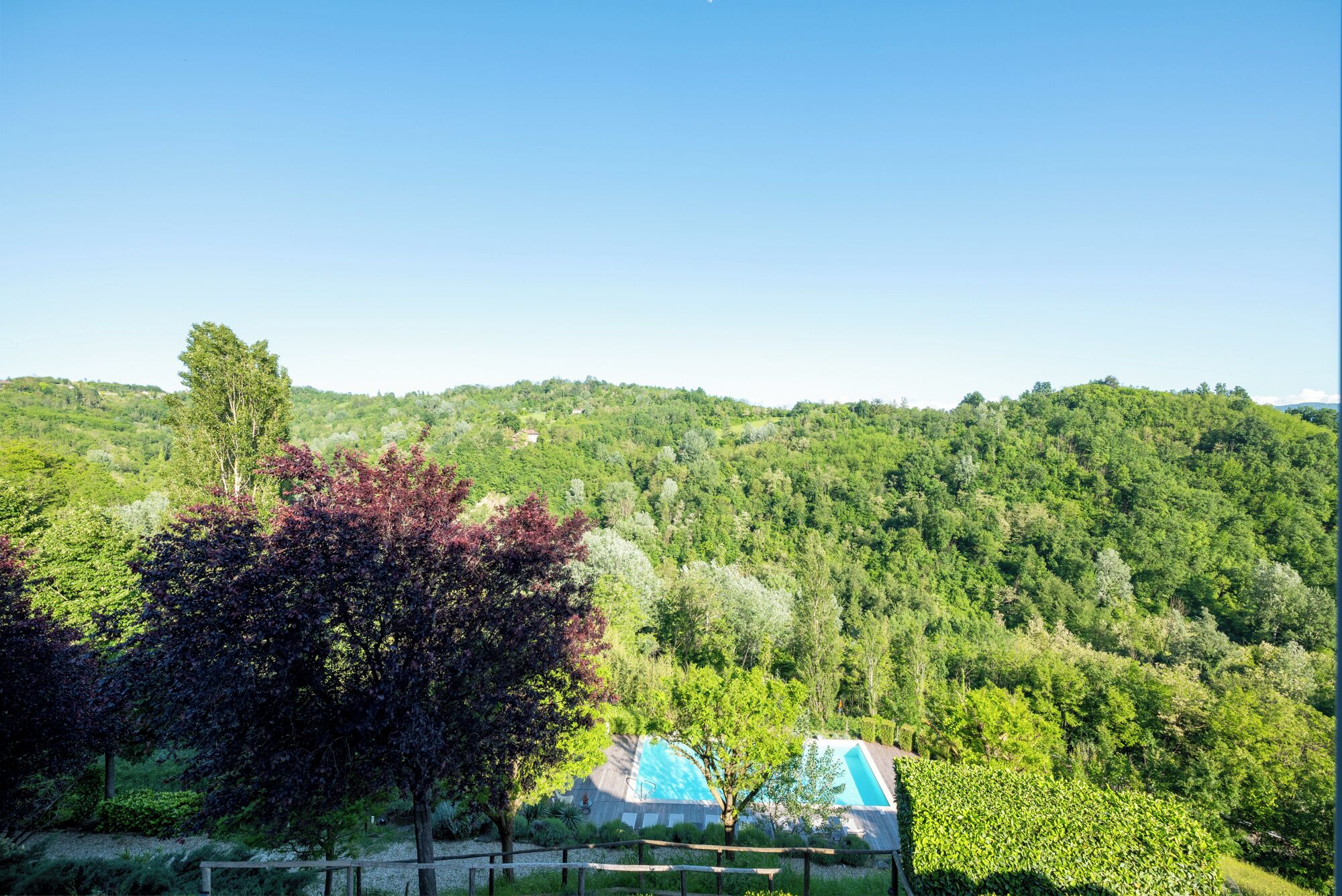 Vista de una ladera boscosa con un área de piscina y dos estructuras cubiertas.