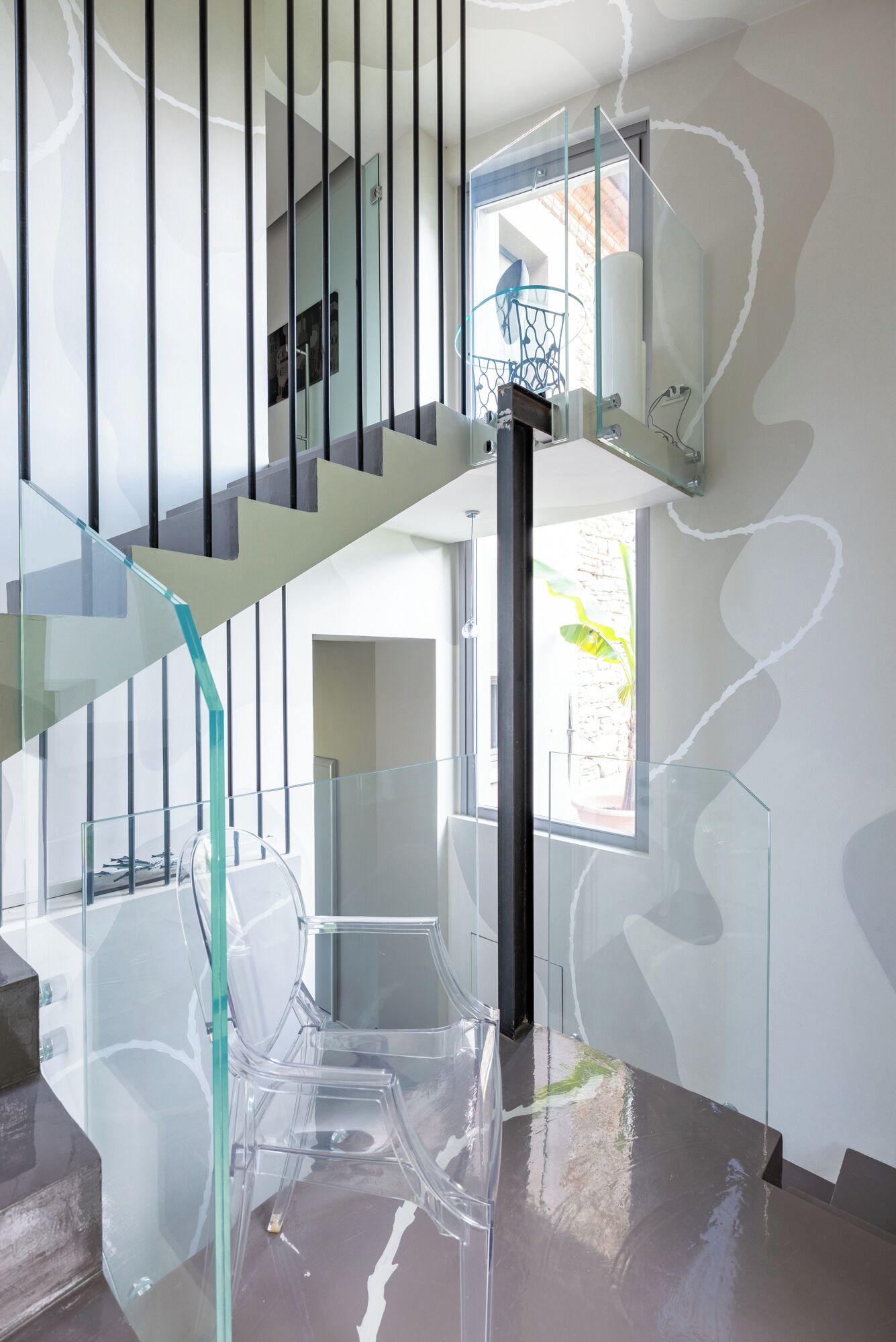 A modern staircase with glass railings and a clear view of the lower level.