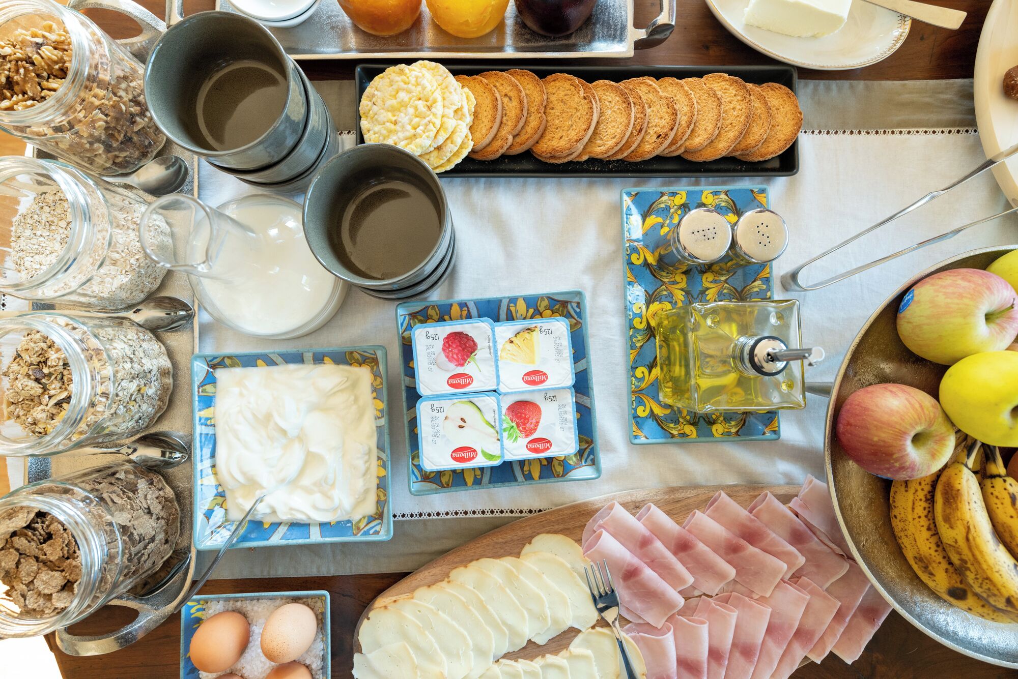 Et morgenbord med forskelligt mad, blandt andet brød, æg, ost og frugt.
