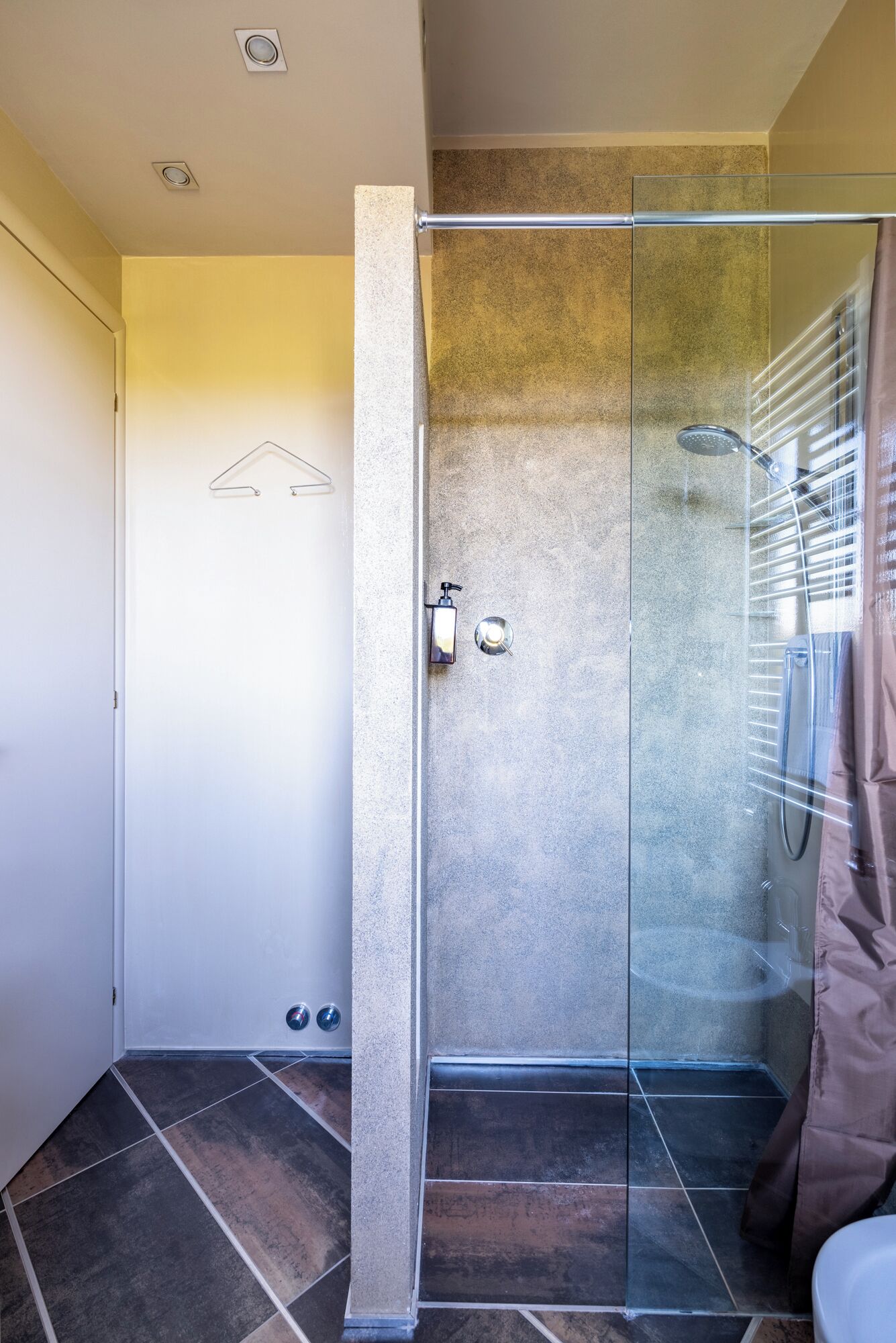 Un baño moderno con cabina de ducha de vidrio, toallero y retrete.