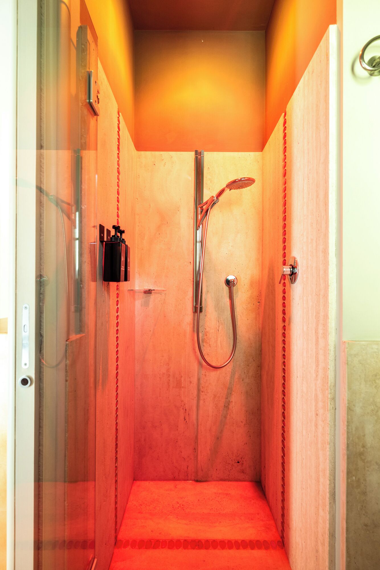 Une petite cabine de douche fermée, dotée d’une porte en verre, d’un pommeau de douche à main et d’un panneau de commande.