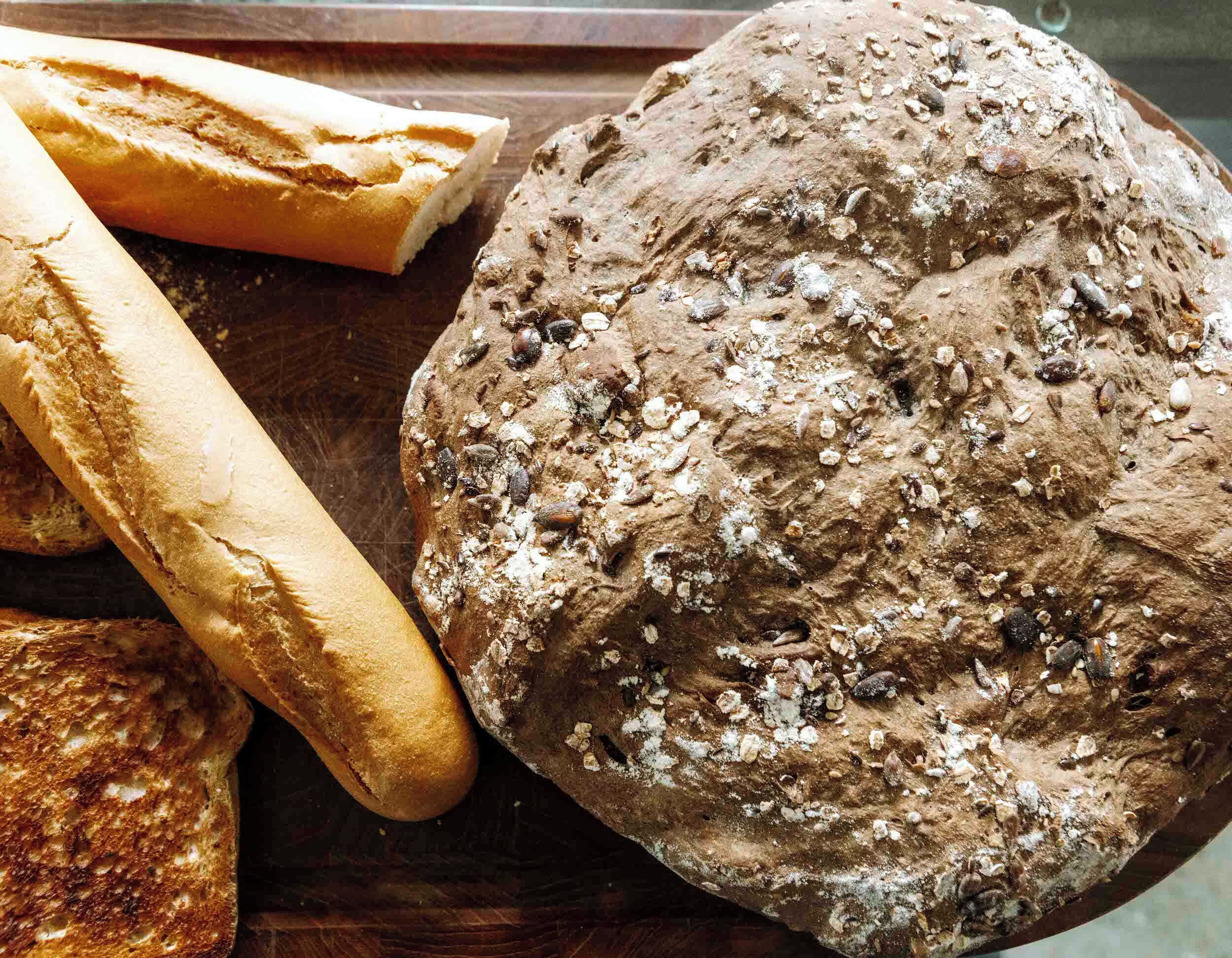 A variety of breads, including a baguette and a round loaf with seeds.