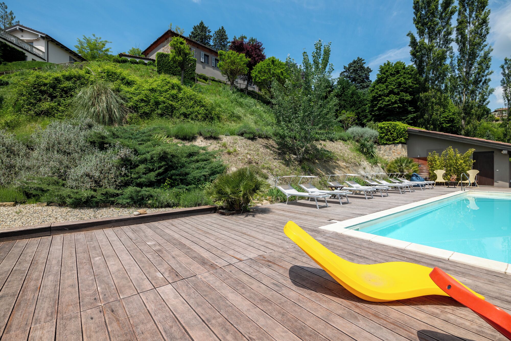 Una terraza de madera con sillones de descanso y una piscina.