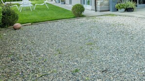 A two-story stone building with a modern design, featuring a gravel driveway and outdoor seating area. - Tenuta Moncarlino (Morsasco)