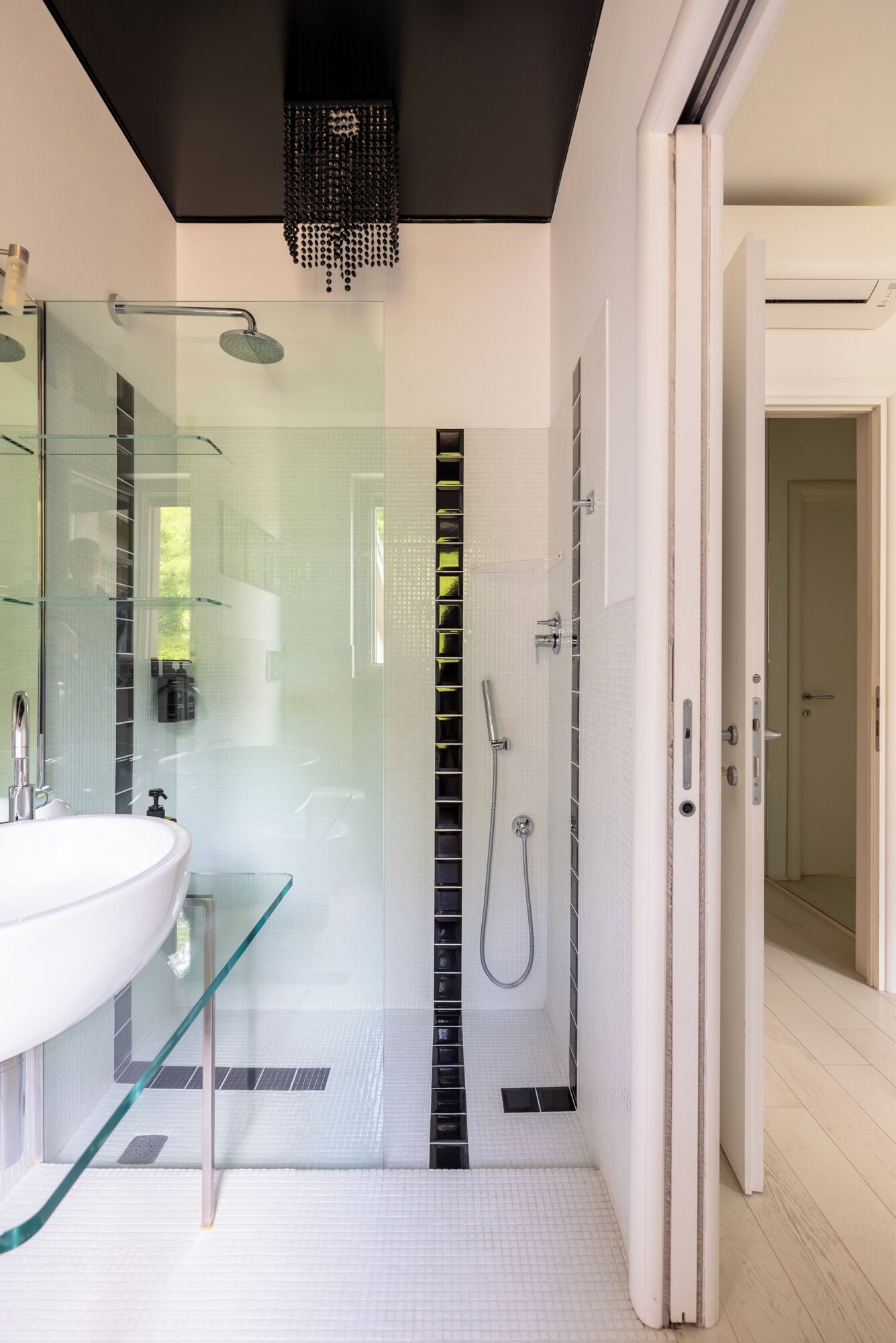 A modern bathroom with a glass-enclosed shower, a white sink, and a walk-in shower.