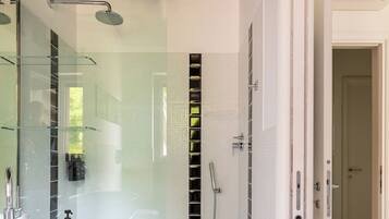 A modern bathroom with a glass-enclosed shower, a white sink, and a walk-in shower.