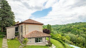 A two-story house with a stone facade and a tiled roof, surrounded by lush greenery and a pool. - Tenuta Moncarlino (Morsasco)