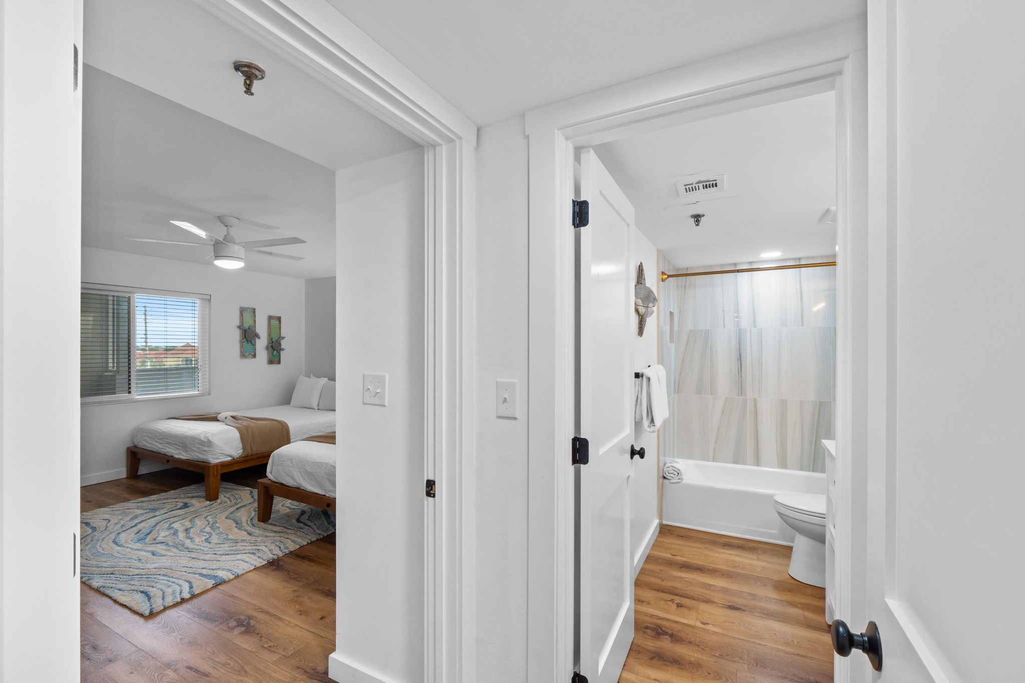 A bedroom with two beds, a ceiling fan, and a window with blinds.