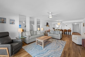 A modern living room with a sofa, coffee table, and a dining area with chairs and a table.