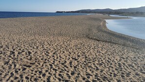 A wide sandy beach with gentle waves, a clear sky, and distant hills. - Coin de Paradis Avec Piscine (Fréjus)