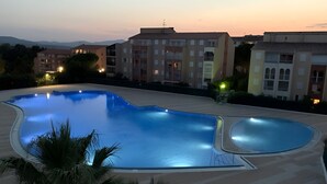 A swimming pool with a curved edge, surrounded by a tiled deck. - Coin de Paradis Avec Piscine (Fréjus)