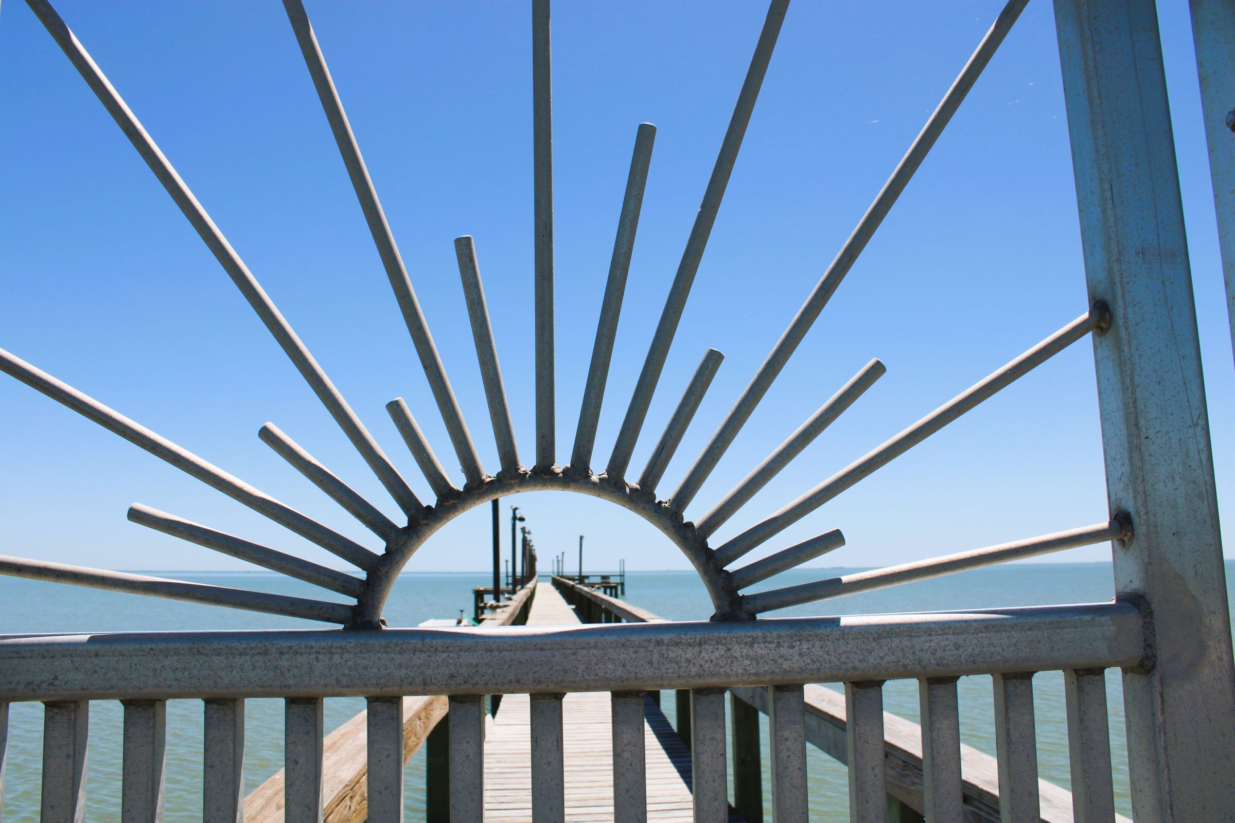 A pier extending into the water with a metal railing in the foreground.