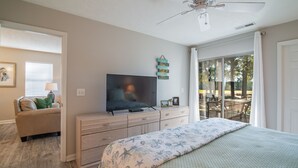 A bedroom with a bed, a TV, a dresser, and a ceiling fan.