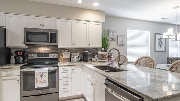 A modern kitchen with white cabinets, stainless steel appliances, and a granite countertop.