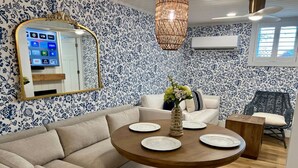 A living room with a round wooden table, beige sofa, and patterned wallpaper. - Albertville Historic Charmer (Albertville)