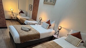 A hotel room with three beds, each with a brown blanket and white linens. There are bedside lamps and a brick wall. - Authentic charm in Corbas: 120m² of comfort (Corbas)