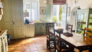 A kitchen with a wooden table and chairs, a refrigerator, and a sink. - Authentic charm in Corbas: 120m² of comfort (Corbas)