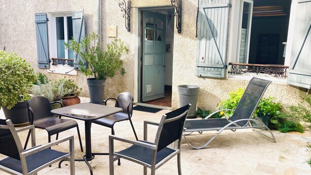 An outdoor patio with a table and chairs, potted plants, and a door leading to the interior. - Authentic charm in Corbas: 120m² of comfort (Corbas)