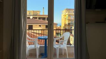 A room with a sliding glass door leading to a balcony with a table and chairs.