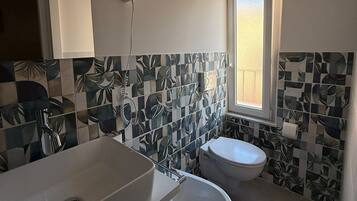 Ein Badezimmer mit Waschbecken, Toilette und einem an der Wand montierten Föhn.