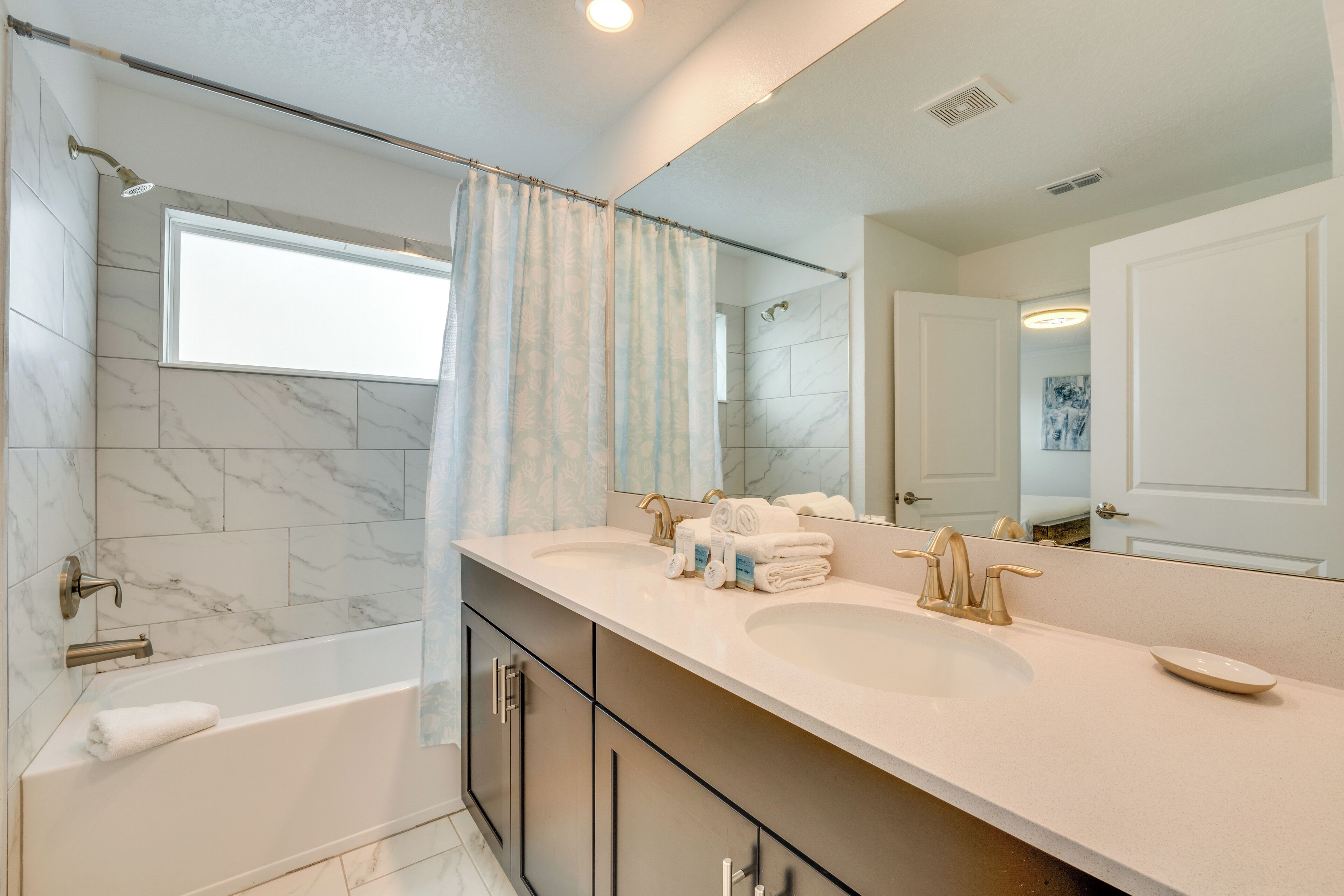 Un bagno moderno con una vasca, due lavabi, un grande specchio e piastrelle in marmo.