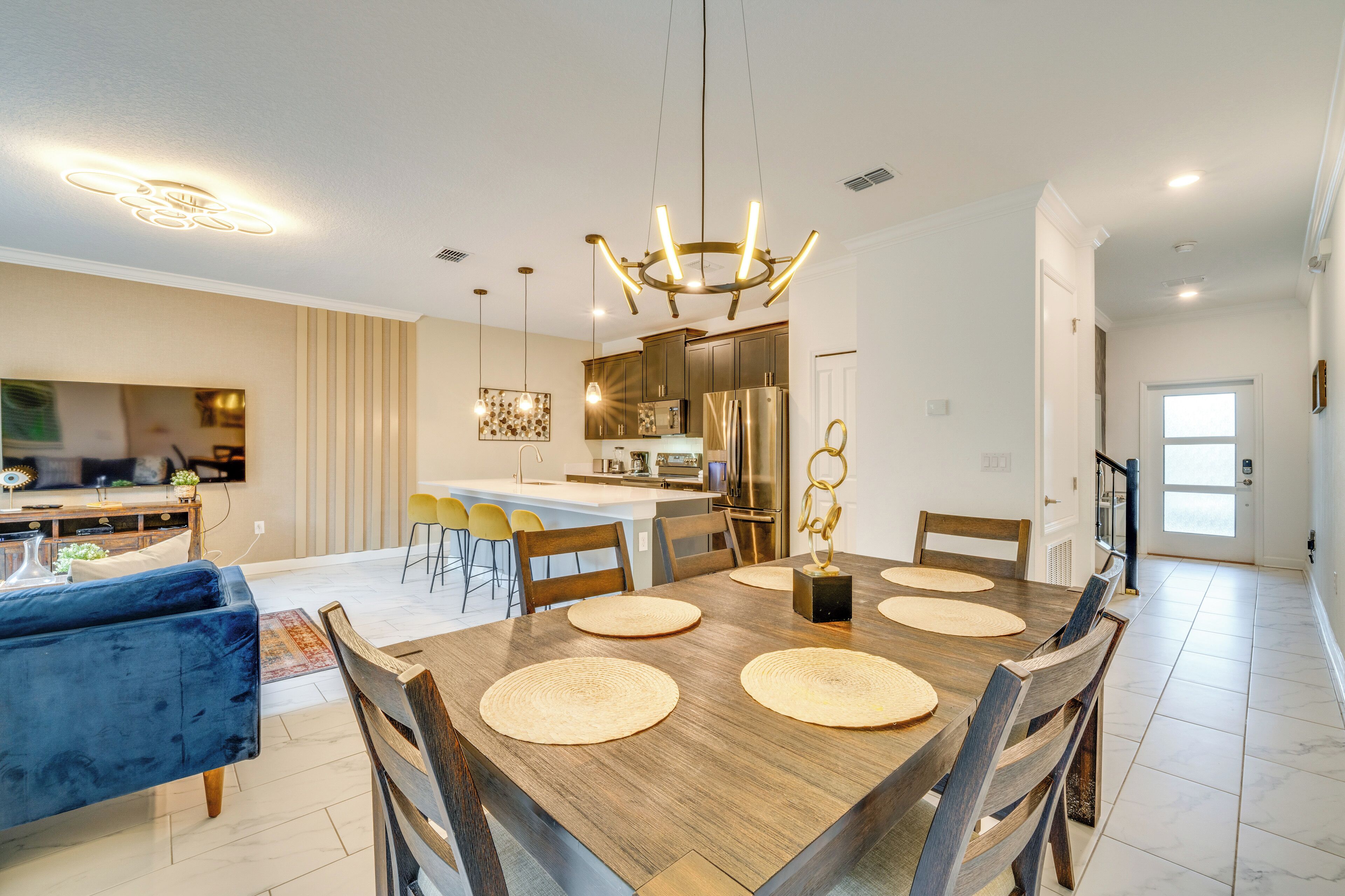 A modern dining area with a wooden table, chairs, and a chandelier.