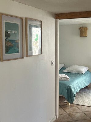 Ein Schlafzimmer mit einem Bett, Kissen, einem gefalteten Handtuch und zwei gerahmten Bildern an der Wand.