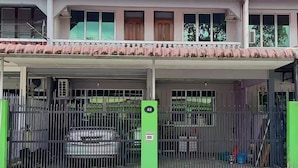 Una entrada con portón a un edificio con zona de estacionamiento techada.