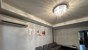 Un área de espera moderna con un sofá gris, una araña de techo y tres obras de arte en la pared.