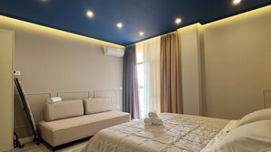 A bedroom with a bed, a sofa, and a ceiling fan.