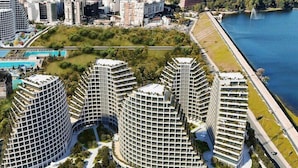 A modern residential complex with curved architecture, a central courtyard, and a waterfront view.