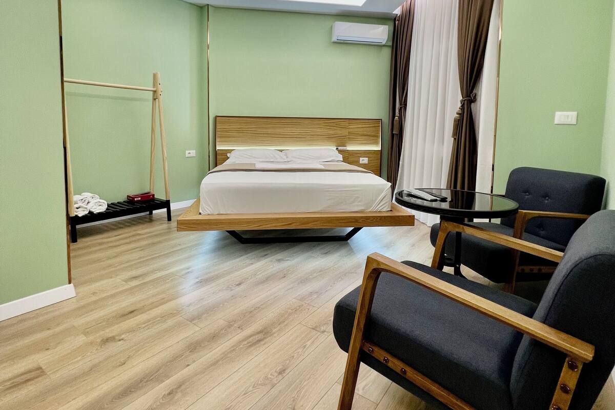 Een moderne hotelkamer met een bed, een zithoek en een plafondlamp.
