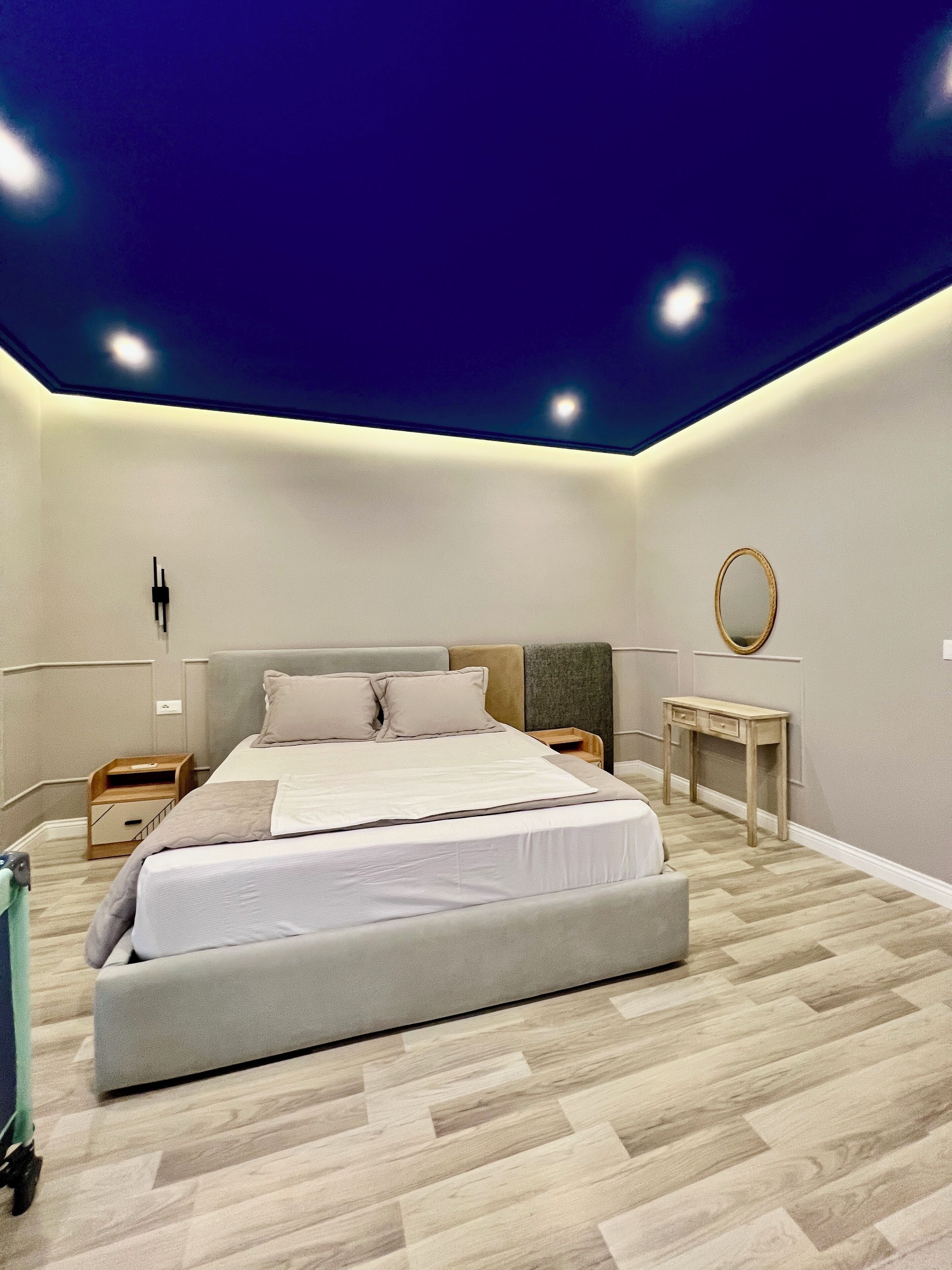 Um quarto moderno com uma cama grande, mesas de cabeceira, uma escrivaninha e um espelho.