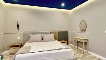 Um quarto moderno com uma cama grande, mesas de cabeceira, uma escrivaninha e um espelho.
