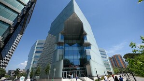 A modern building with a prominent glass facade and a unique angular design.